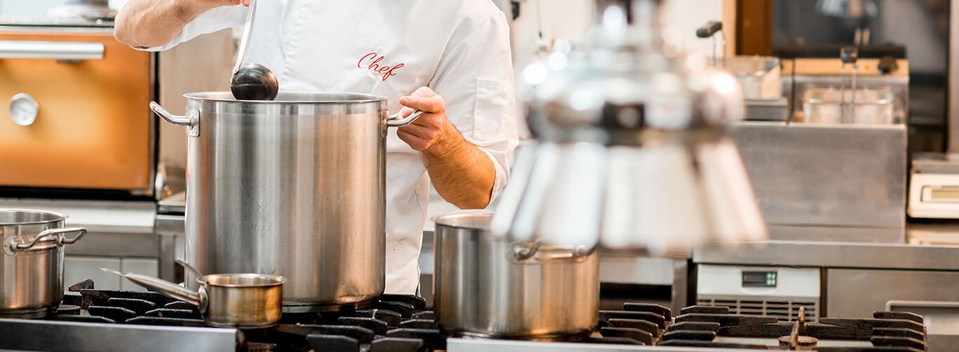 Koch kocht Suppe in großem Topf